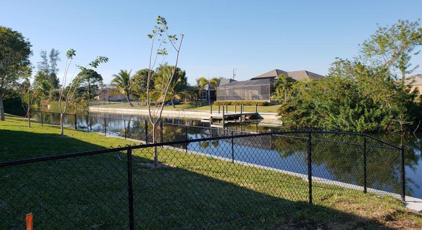chain-link fence installed in backyard by canal